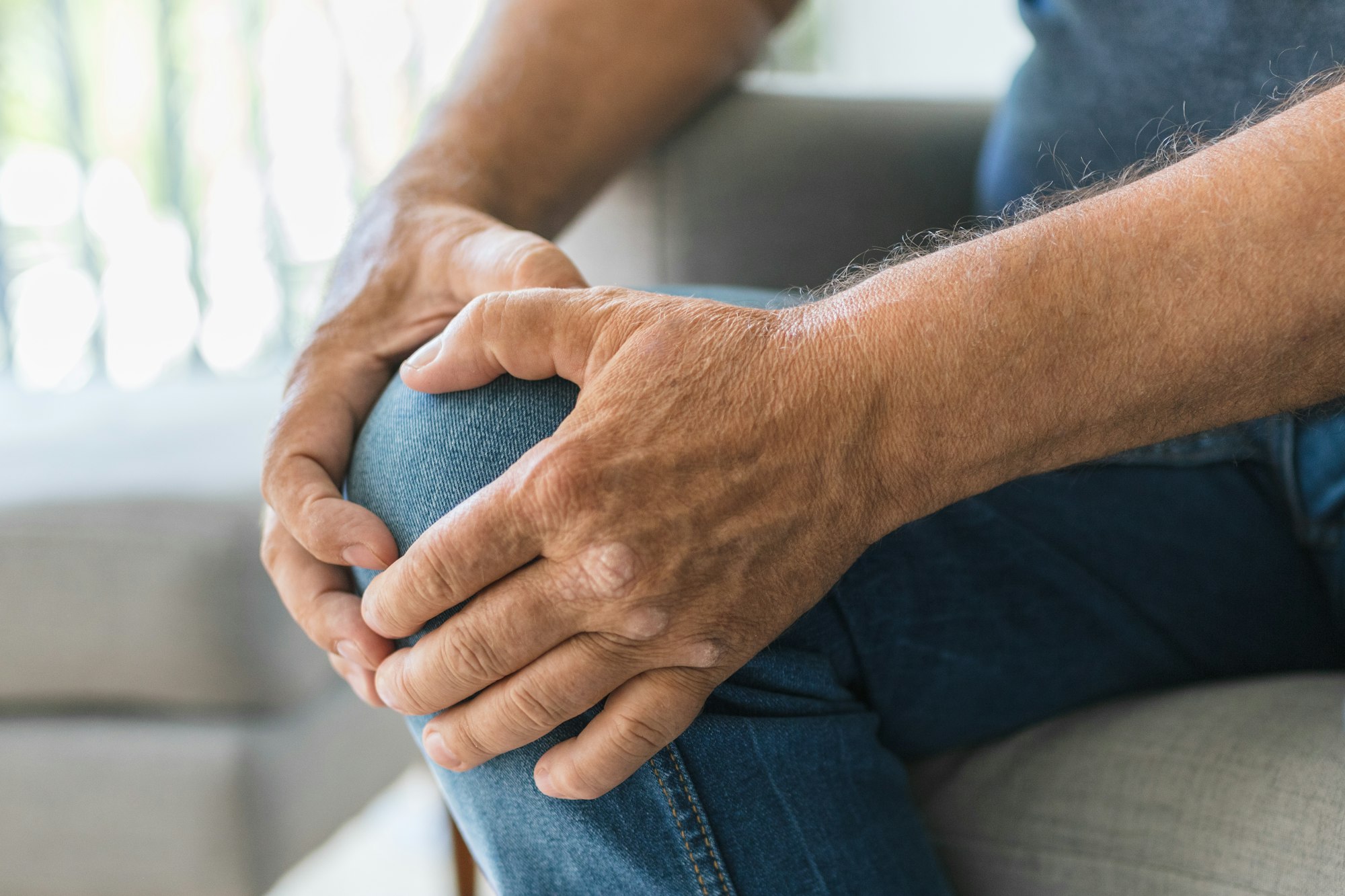 A man sitting on the couch holding his knee.