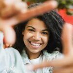 A woman smiling and making a hand sign.