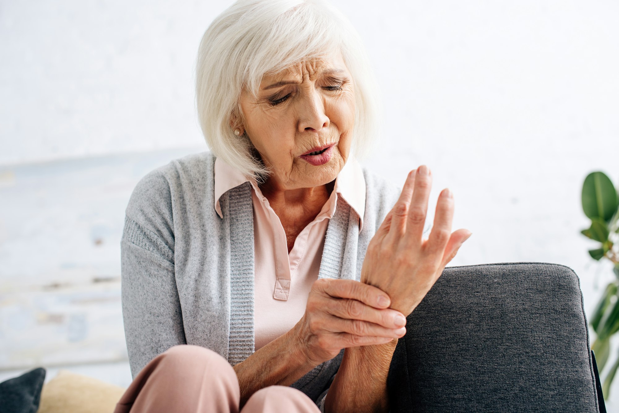 A woman sitting on the couch with her hands in front of her.