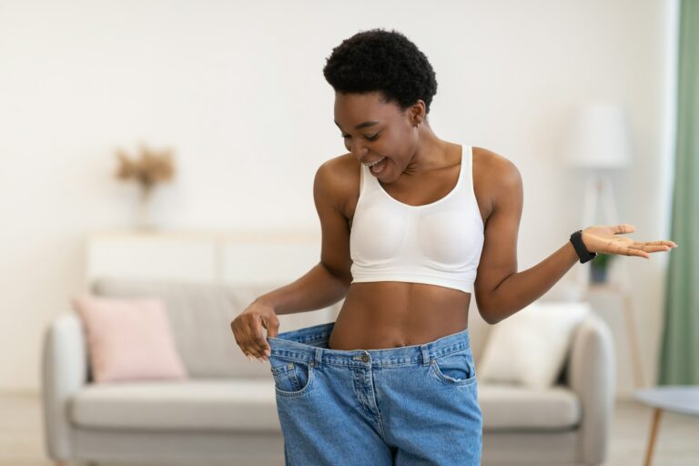 A woman in white top and blue shorts holding a phone.