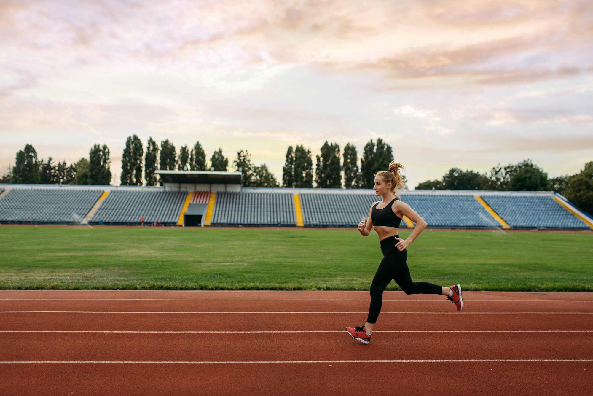 A woman running on the track in an athletic field.