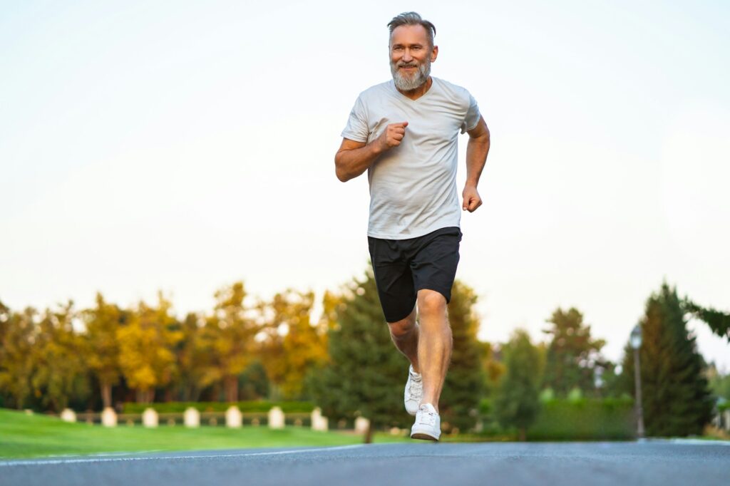 A man running on the road in front of trees.